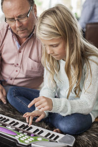 Grandfather and granddaughter playing piano at home