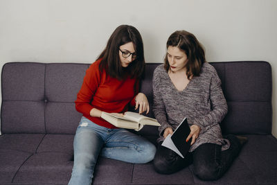 Young woman using phone while sitting on sofa