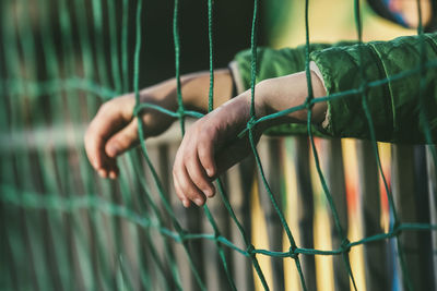 Close-up of hand holding metal fence against blurred background