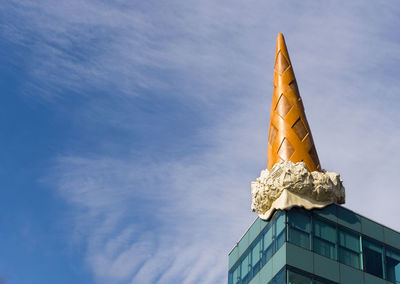 Low angle view of ice cream cone sculpture on building against sky