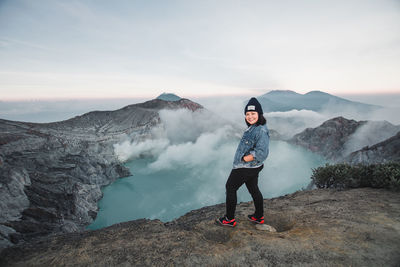 Full length of woman standing on mountain against sky