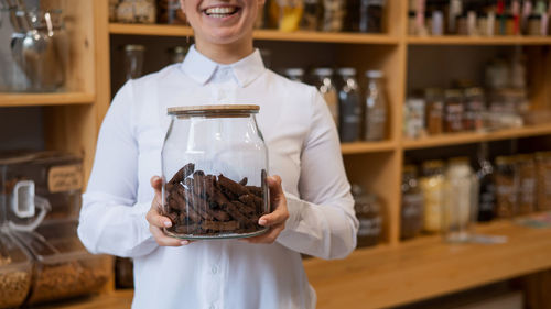 Midsection of woman holding food at store in jar