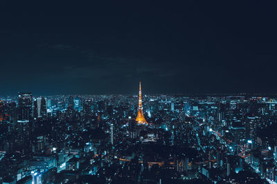 Illuminated tokyo tower amidst buildings against sky at night