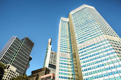 Low angle view of modern buildings against clear blue sky