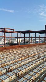 Low angle view of metallic railing against blue sky