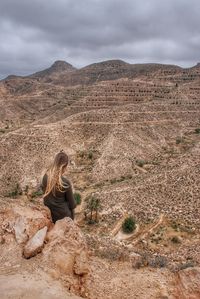 Man sitting on rock against mountain