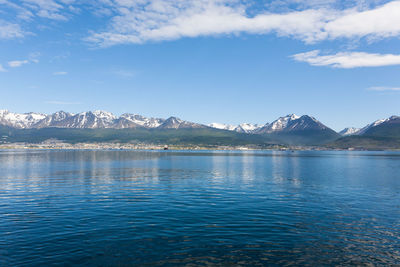 Scenic view of lake by snowcapped mountains against sky