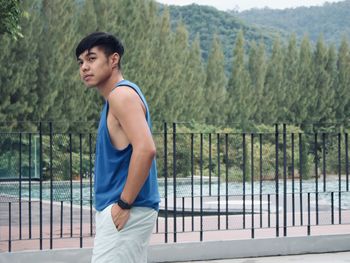 Side view of young man standing against railing