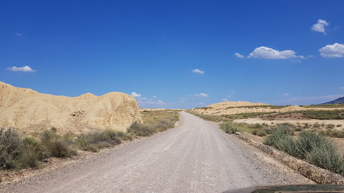 Road amidst land against sky