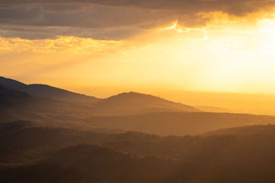 The sun shines over a mountain range in the northern black forest during the golden hour