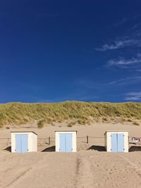 Scenic view of beach cabins against blue sky