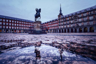 Statue in city against sky