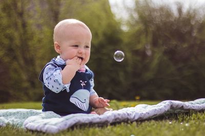 Cute baby girl looking at bubble in park