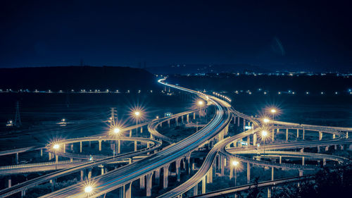 Illuminated light trails on bridge against sky at night