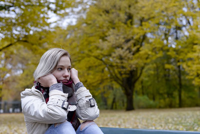 Sad woman sitting in park during autumn