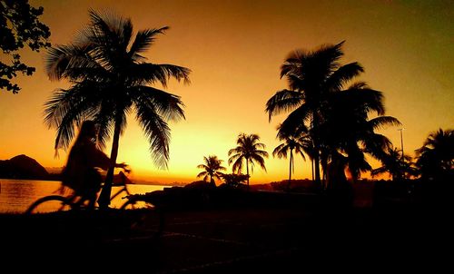 Silhouette palm trees on beach against sky during sunset