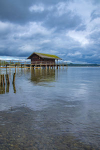 Stilt house on sea against sky