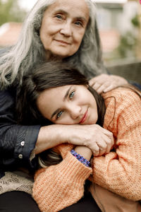 Portrait of smiling girl holding hand and embracing grandmother