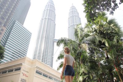 Low angle view of woman with skyscrapers against sky