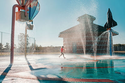 Full length of girl standing amidst water fountain
