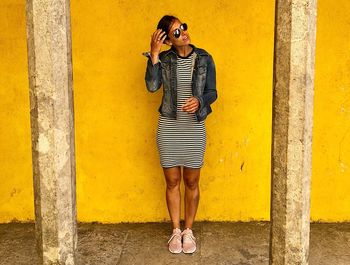 Full length of woman standing against yellow wall