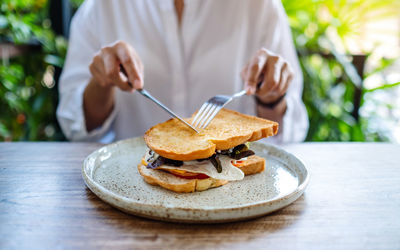 Closeup image of a woman eating ham cheese sandwich