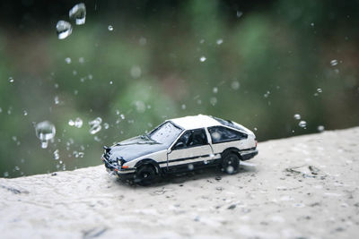 Close-up of toy car on retaining wall during rainy season
