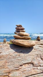 Stack of rocks on beach against clear blue sky
