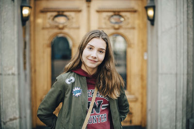 Portrait of smiling girl standing against building