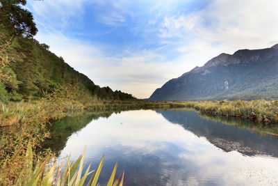 Scenic view of lake by mountains against sky