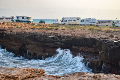 Scenic view of rocks by sea against sky