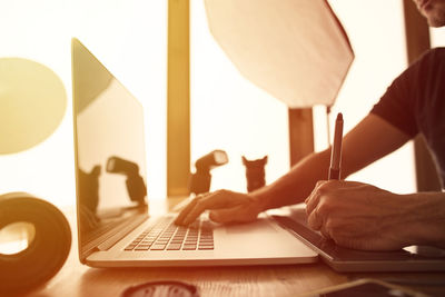 Close-up of man using laptop on table at home