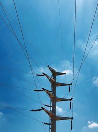 Low angle view of electricity pylon against blue sky