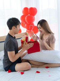 Side view of couple sitting on balloon