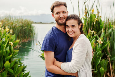Portrait of couple embracing by lake