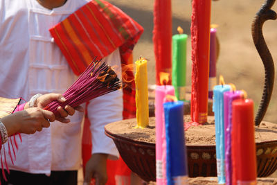 Cropped image of hand holding cross at temple, burning incense,candles, worshiping gods.