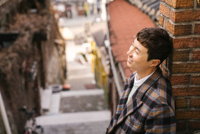 Portrait of young man standing against wall