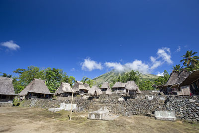 Houses by trees and buildings against blue sky