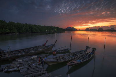 Boats moored in lake against sky during sunset