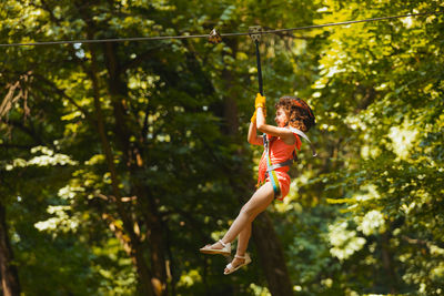 Low angle view of man jumping hanging on tree