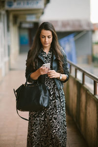 Woman wearing dress texting on the smart phone and walking around.