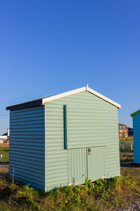 House on field against clear blue sky