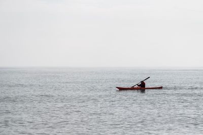 Man sailing boat on sea against sky