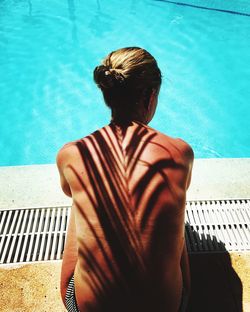 Rear view of woman standing by swimming pool