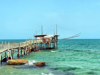 Pier over sea against clear blue sky