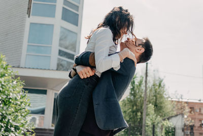 Romantic man carrying woman while standing in city