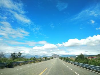 Road passing through landscape against cloudy sky