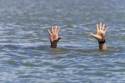 Cropped hands of person dangerin sea