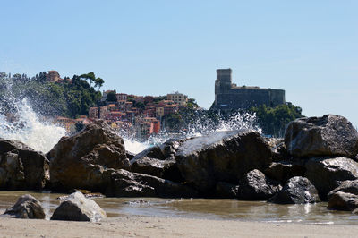 Panoramic shot of rocks by sea against clear sky