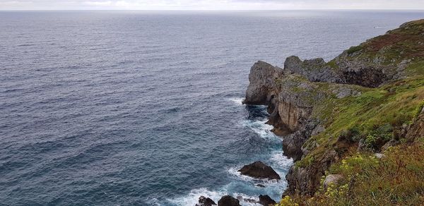 Rock formation on sea shore against sky